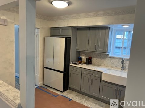 A kitchen with a refrigerator, cabinets, and a countertop.