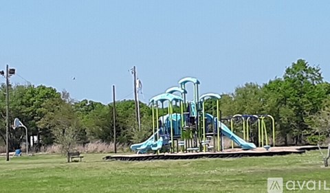 A playground with a blue slide and a green lawn.