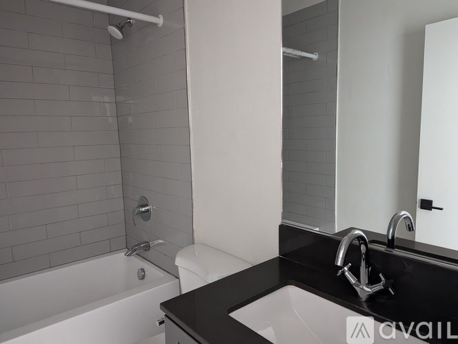 A white bathtub with a shower head and a white toilet in a bathroom.