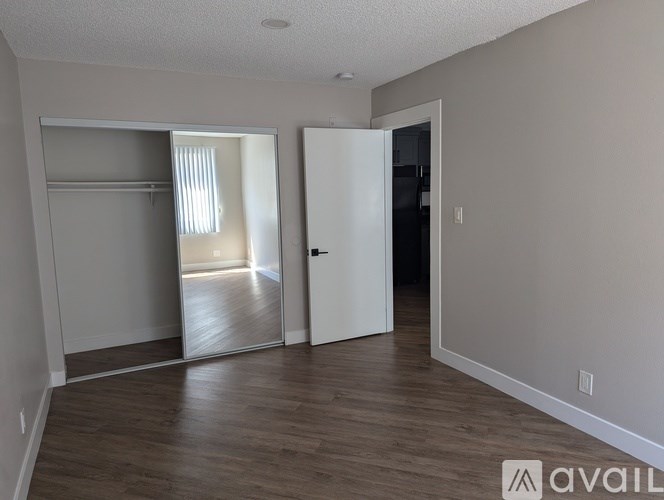 A room with a white door and a white closet with a mirror.