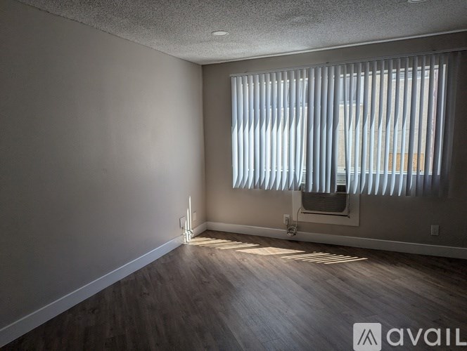 A room with wooden floors and a window with blinds.