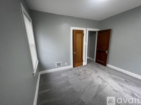 A room with grey walls and a carpeted floor with a door and a window.