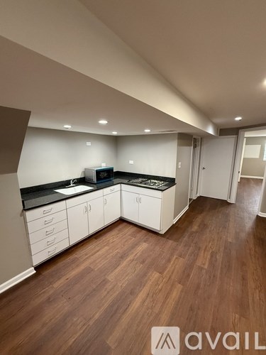 A kitchen with white cabinets and a wooden floor.