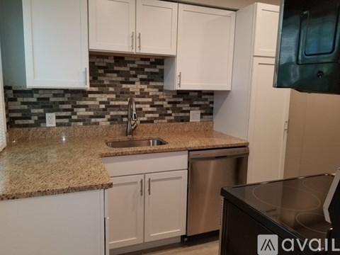 A kitchen with white cabinets and a granite countertop.