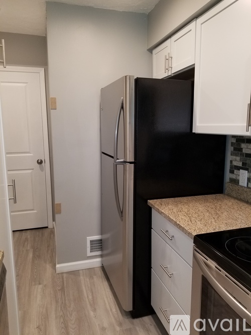 A kitchen with a black fridge and white cabinets.