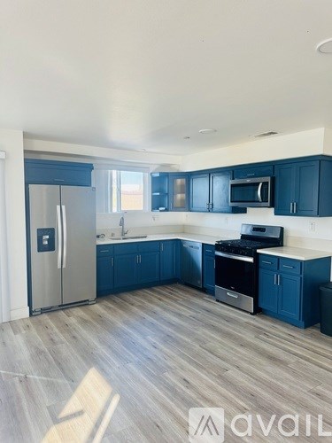 A kitchen with dark blue cabinets and a stainless steel refrigerator.