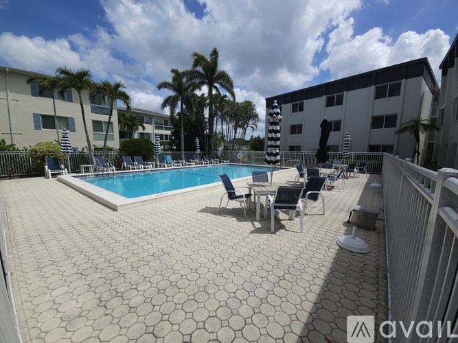 A pool surrounded by chairs and palm trees.