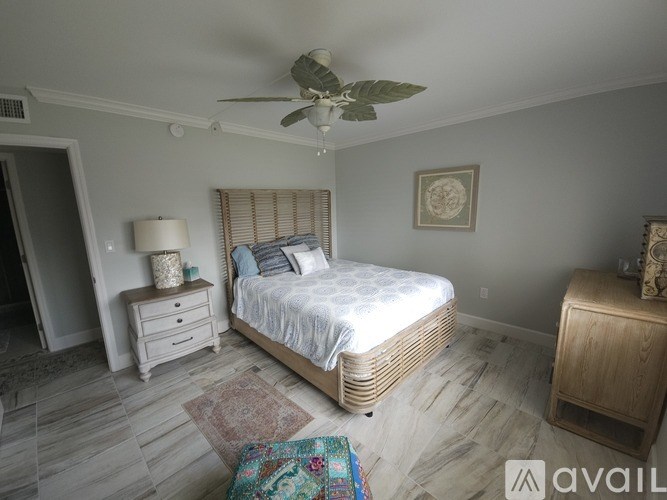 A bedroom with a bed, nightstand, and a ceiling fan.
