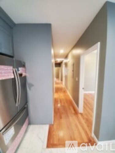 A kitchen with a stainless steel refrigerator and wooden flooring.