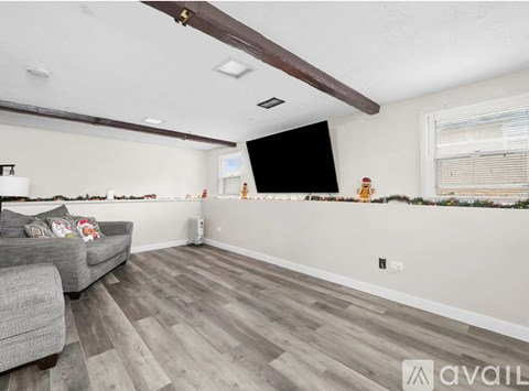 A living room with a grey couch and a flat screen TV mounted on the wall.
