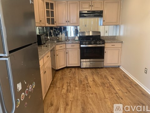 A kitchen with a black fridge and wooden floors.