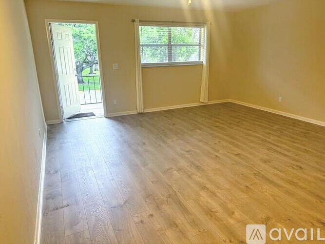 A room with wooden flooring and a door leading outside.
