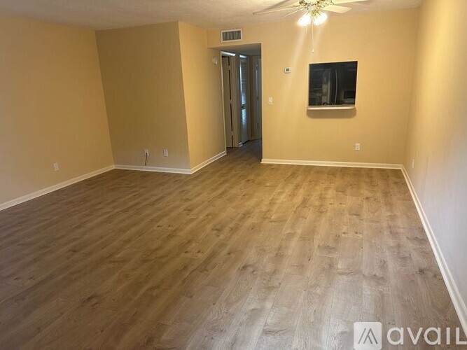 A spacious room with wooden flooring and a television mounted on the wall.