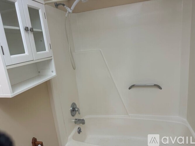 A white bathroom with a tub and a cabinet above it.