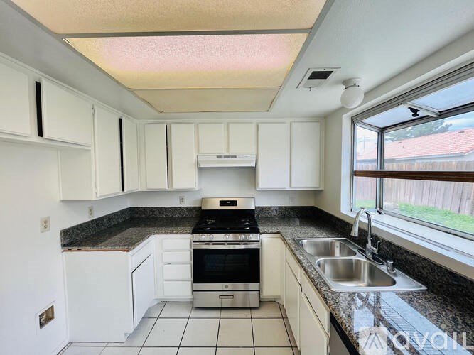A kitchen with white cabinets and a black stove top oven.