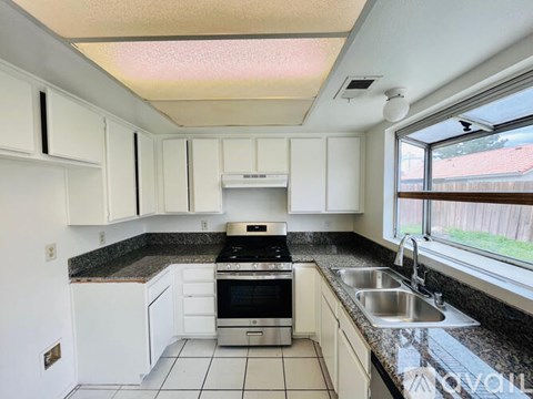 A kitchen with white cabinets and a black stove top oven.