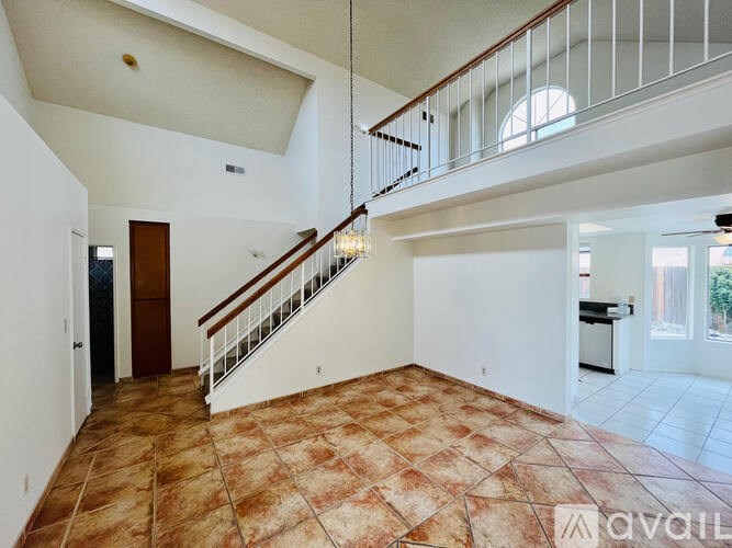 A large open space with a tiled floor and a staircase with a metal railing.