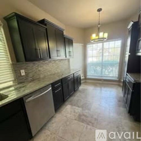 A kitchen with black cabinets and a marble countertop.