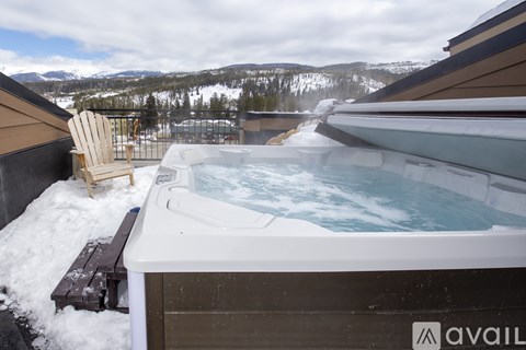 A hot tub on a balcony with snow on the ground and mountains in the background.