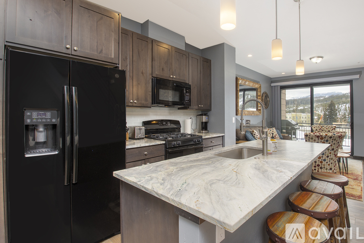 A kitchen with a black refrigerator and a marble countertop.