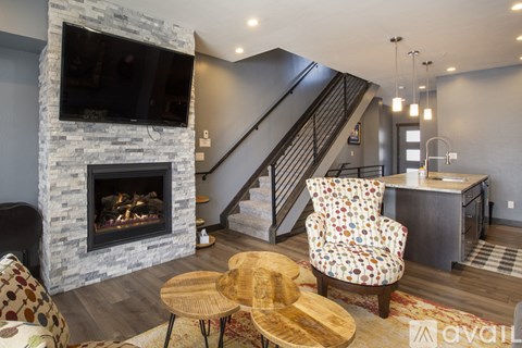 A living room with a stone fireplace and a chair with a multicolored pattern.