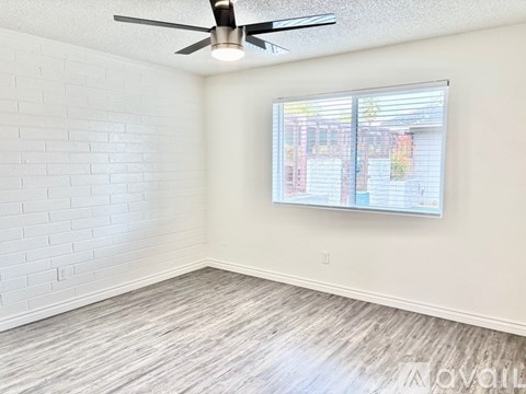 A room with a ceiling fan and a window with blinds.