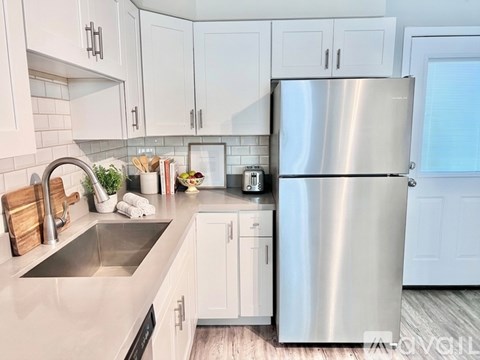 A spacious kitchen with white cabinets and a grey floor.