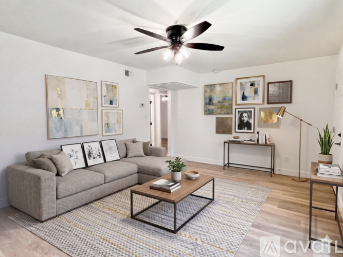 A living room with a grey couch, a coffee table, and a ceiling fan.