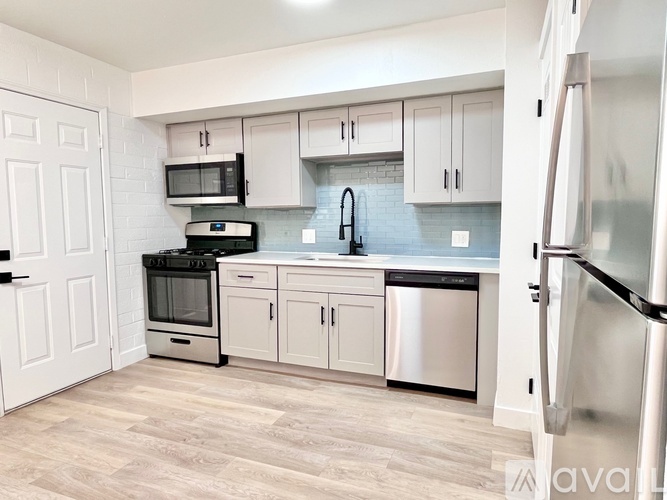 A kitchen with white cabinets and a black fridge.