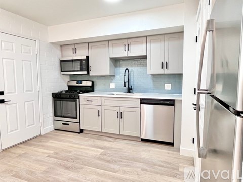 A kitchen with white cabinets and a black fridge.
