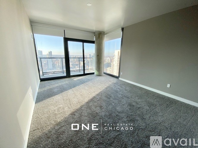 A room with a carpeted floor and a view of the city through large windows.