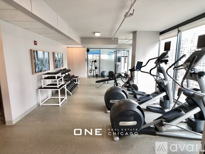 A gym with a row of treadmills and elliptical machines.