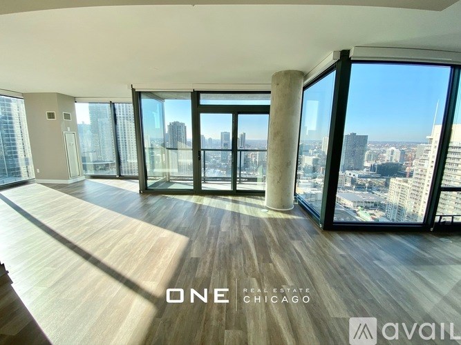 A spacious room with wooden floors and large windows overlooking a cityscape.