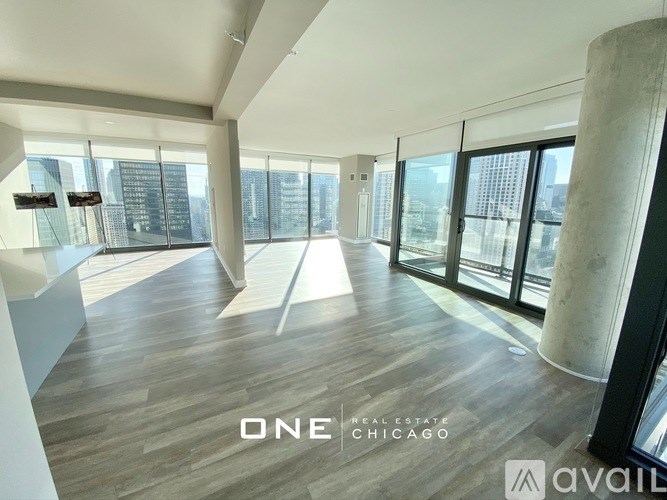 A spacious room with wooden floors and large windows overlooking a cityscape.