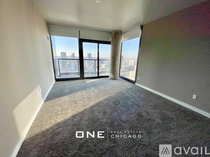 A room with a carpet floor and a view of the city through the windows.