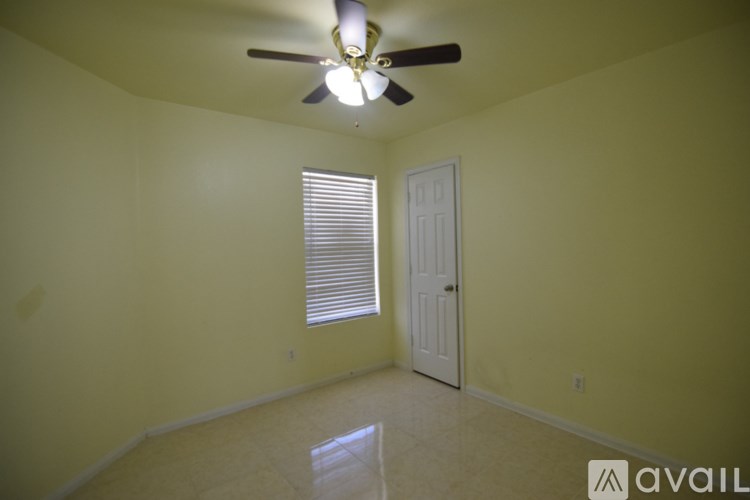 A room with a ceiling fan and a window with blinds.