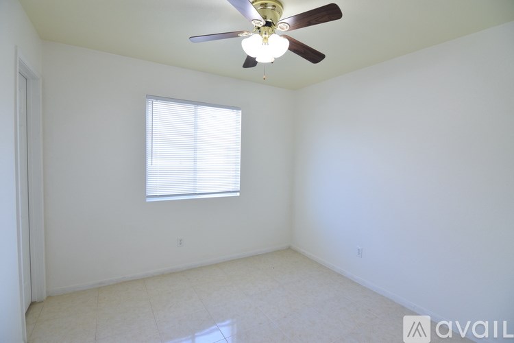 A white house with a brown roof and a fence in front of it.