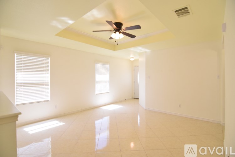 A spacious room with a ceiling fan and two windows.
