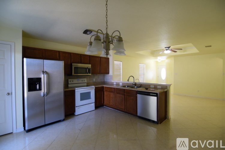 A kitchen with a refrigerator, microwave, oven, sink and cabinets.
