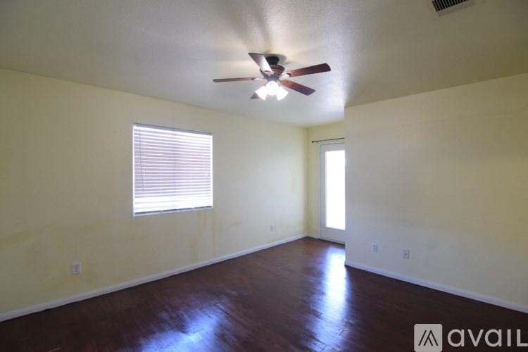 A room with a ceiling fan and two windows.