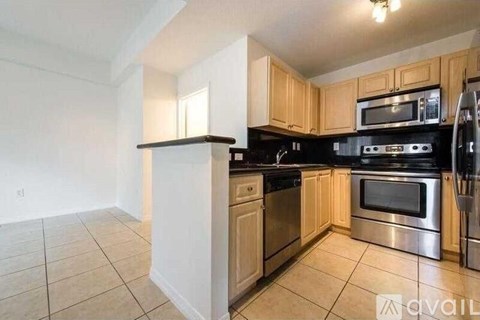 A kitchen with wooden cabinets and stainless steel appliances is available for rent.
