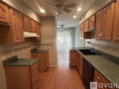 A kitchen with wooden cabinets and a fan on the ceiling.