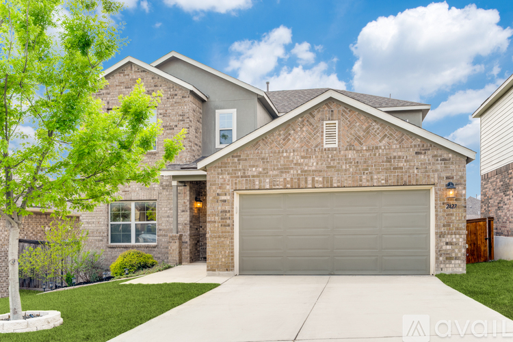 A house with a garage and a tree in front.