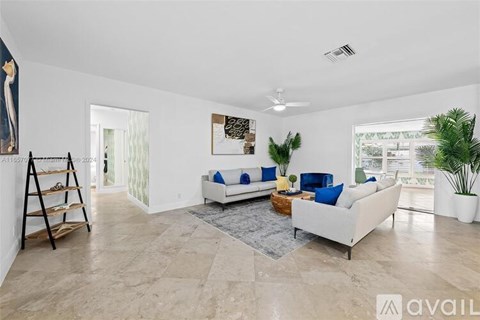 A spacious living room with a white sofa and a rug in the center.