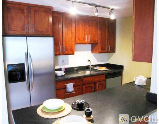 A kitchen with wooden cabinets and a stainless steel refrigerator.