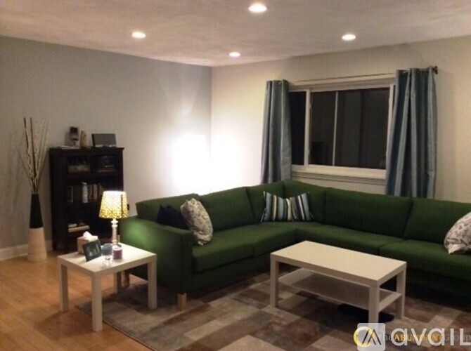A living room with a green couch, a white coffee table, and a lamp.
