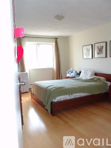 A bedroom with a bed, nightstand, and window.