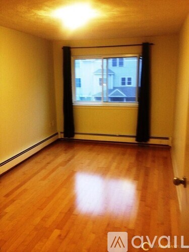 A room with wooden floors and a window showing a building outside.