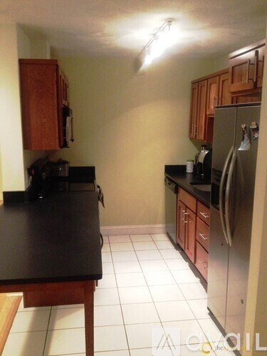 A kitchen with a black counter top and white tile floor.
