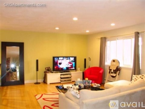 A living room with a white couch and a television on a white stand.